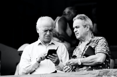 在戴着模拟手表的男人旁边，一个男人正在用智能手机
